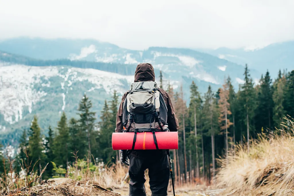 Man standing on a mountain, with a backpack.