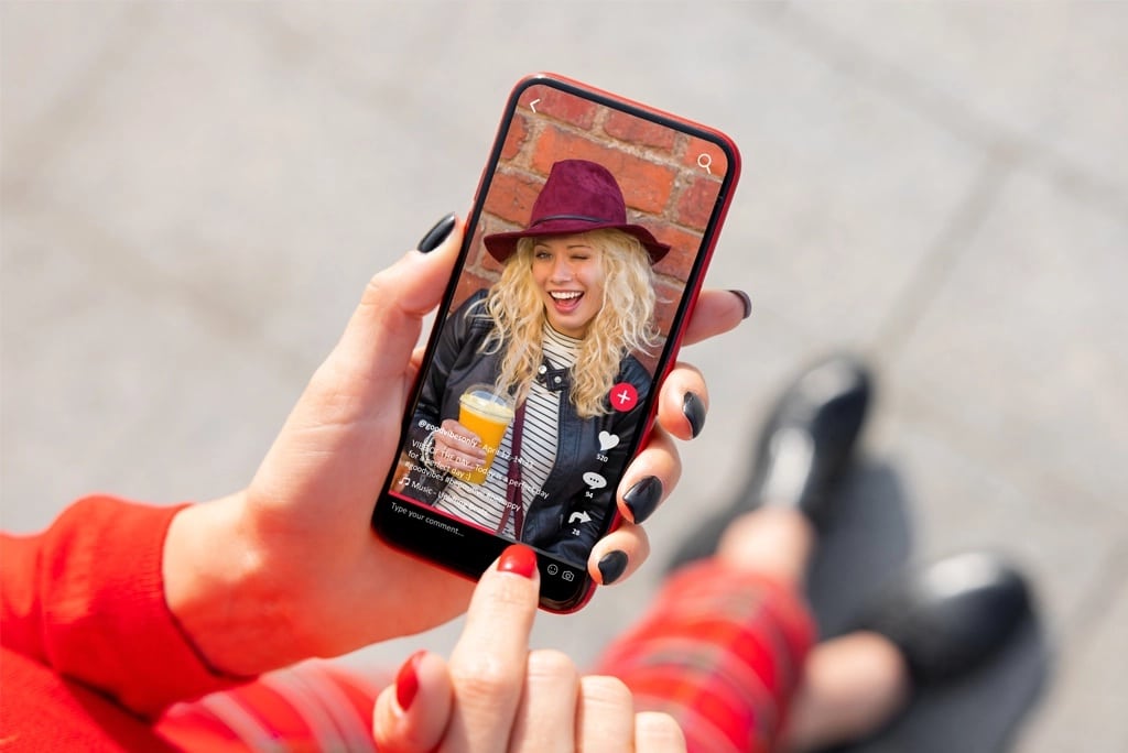 Adllins-Media-Blog-Social-Media-Trends | Adllins Media Hands holding a smartphone with a blonde woman in a hat on the screen